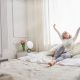 Image d’une femme qui s’étire sur son lit, moment de bien-être pour illustrer l’importance du capital santé»